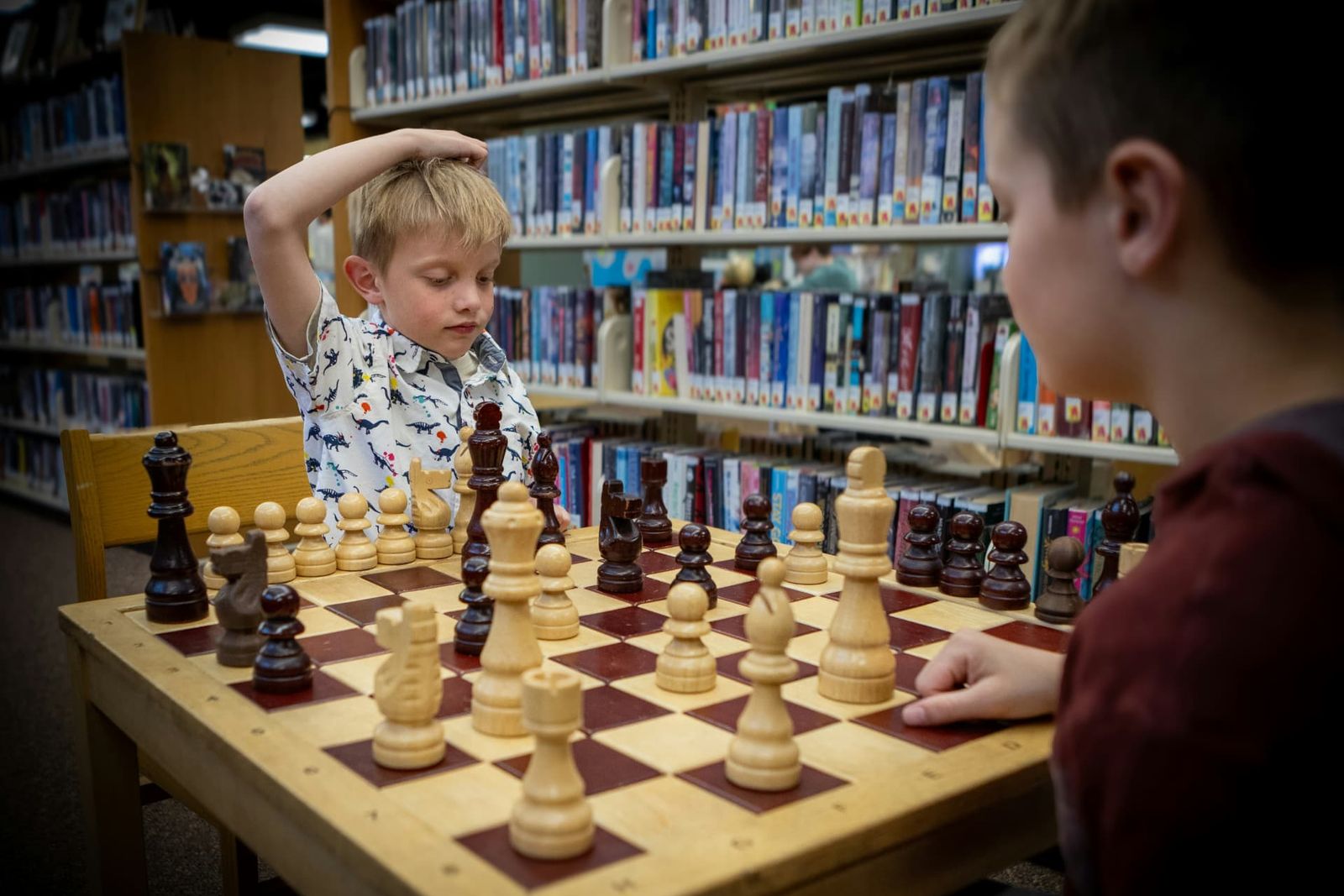 Two boys playing chess together in a public library