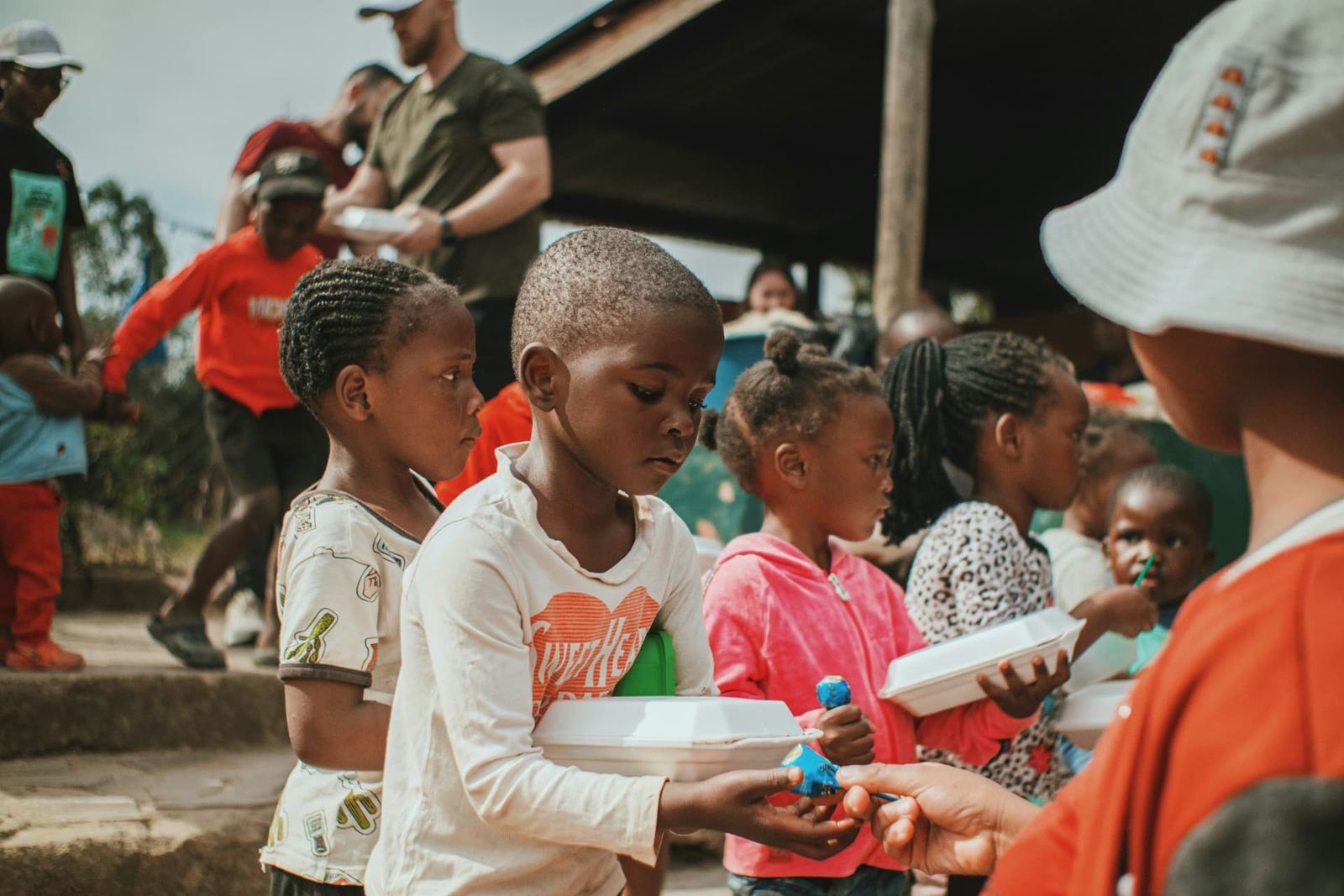 Children receiving warm meals from volunteers at a community distribution