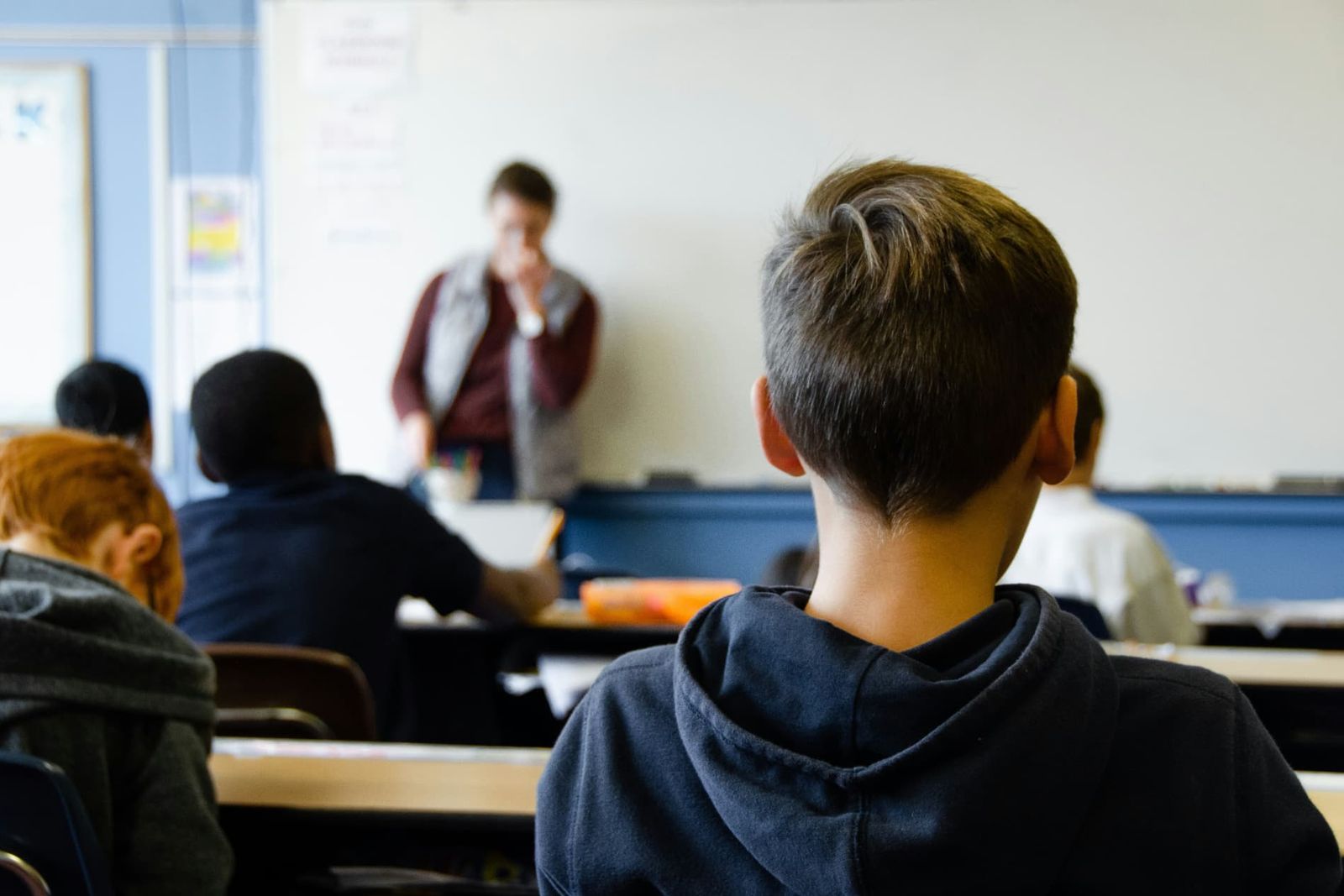 Pupils listening to their teacher at the front of a primary school classroom