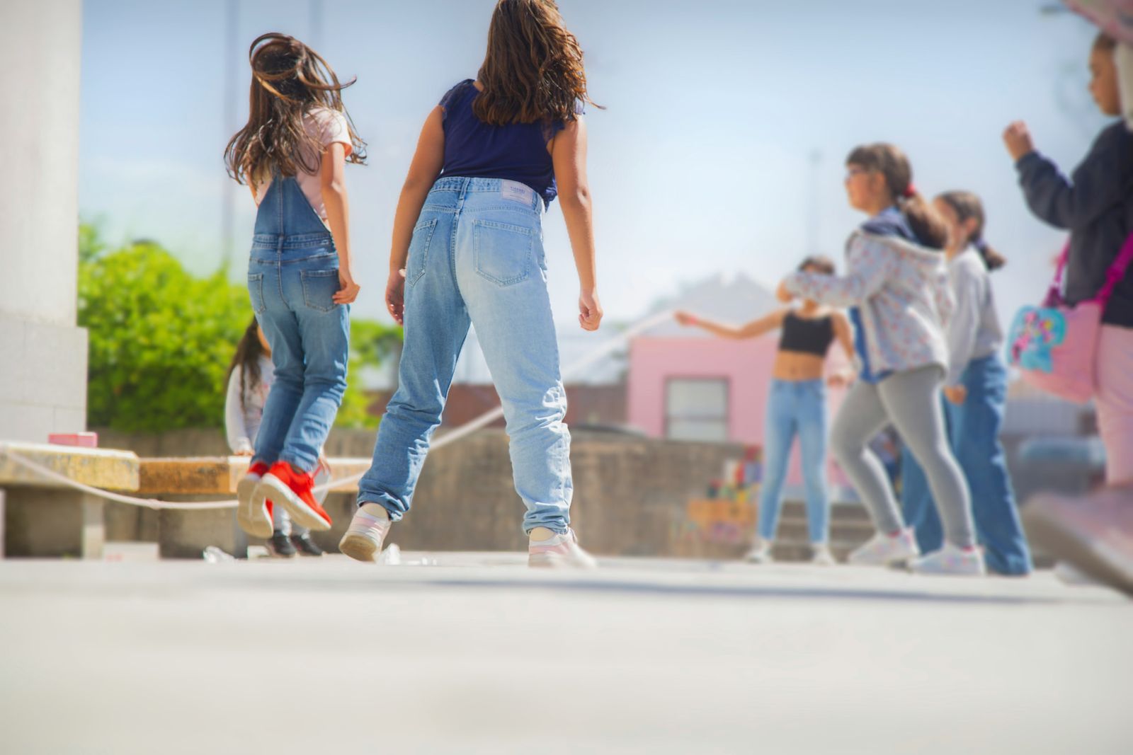 Children skipping rope together in a sunlit schoolyard