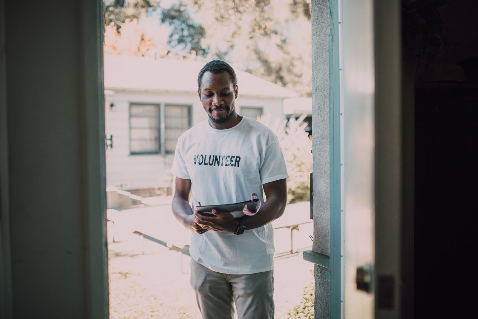 A volunteer taking notes on a doorstep during a household outreach visit