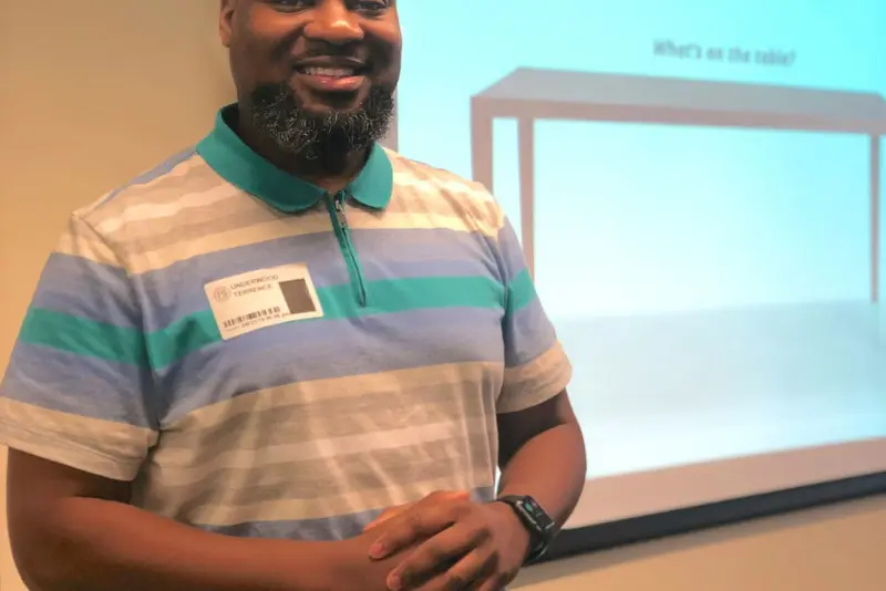 A trainer smiling beside a projected slide during a digital skills workshop